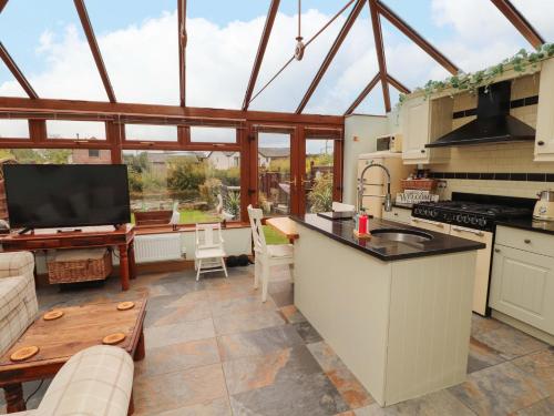 a kitchen and living room in a conservatory at Beckside Cottage in Penrith