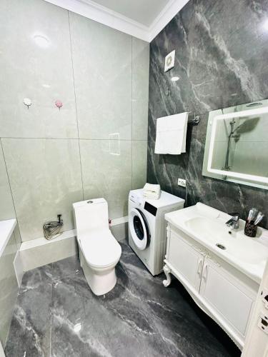 a bathroom with a toilet a sink and a washing machine at Komfort City Residential Fam Luxe Complex with Mountain View in Zhezdi