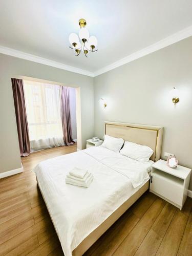 a bedroom with a white bed with two towels on it at Komfort City Residential Fam Luxe Complex with Mountain View in Zhezdi