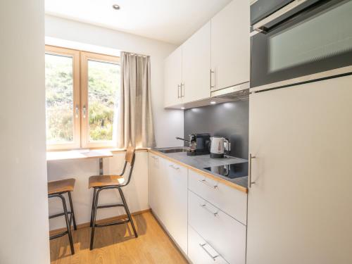 a kitchen with white cabinets and a table and chairs at Appartements Basecamp Warth in Warth am Arlberg