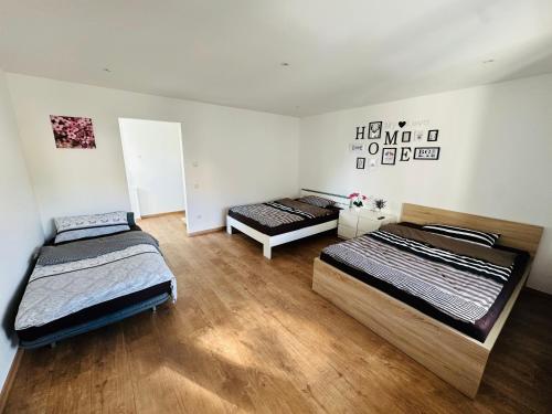 two beds in a room with wooden floors at Große 2 Ferienwohnung Gästehaus NEUBAU Merzig 100 m2 in Merzig