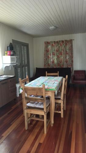 einen Tisch und Stühle in einem Zimmer mit Holzböden in der Unterkunft Chalé Paraíso Da Serra 01 in Gramado