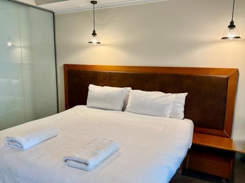 a bedroom with a white bed with two towels on it at HAVEN by the Sea in Mandurah