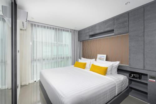 ein Schlafzimmer mit einem großen weißen Bett mit gelben Kissen in der Unterkunft City Gate Kamala B216 by Phuket Sabay Rent in Phuket
