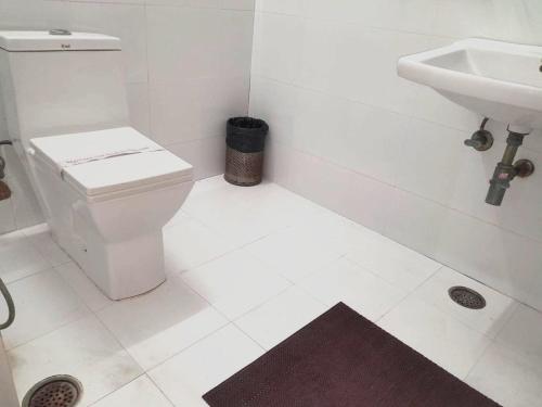 a white bathroom with a toilet and a sink at Little Ganesha Inn in Jaipur