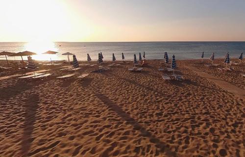 a beach with chairs and umbrellas and the ocean at 12 senses faliraki sea view in Faliraki
