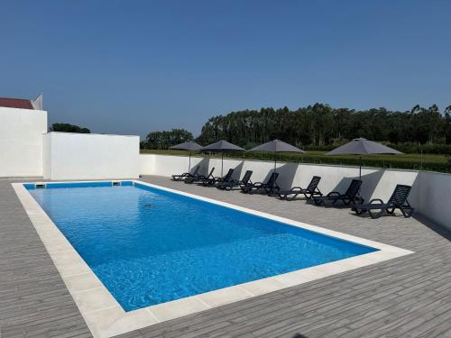 a swimming pool with chairs and umbrellas at Lugar do Paraíso - Casa do Armazém - Vila do Conde in Touguinho