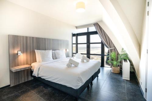 a bedroom with a large bed and a large window at Poort Beach Boutique Apartments in Bloemendaal Aan Zee