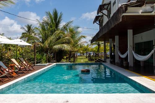 a swimming pool next to a building with palm trees at Bella Gamboa Casa de Praia - Gamboa, Morro de São Paulo - in Gamboa
