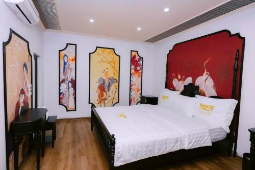 a bedroom with a large bed with paintings on the wall at Favos Resort Ninh Binh in Vũ Lâm