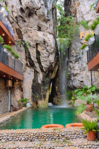 a swimming pool with a waterfall in front of a mountain at Favos Resort Ninh Binh in Vũ Lâm