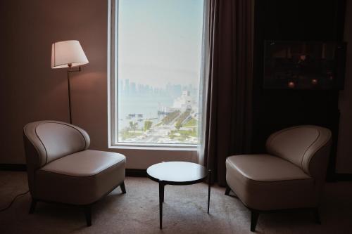 a room with two chairs and a table and a window at Horizon Manor Hotel in Doha