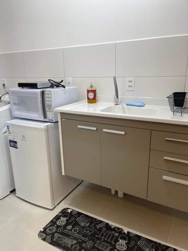 a kitchen with a sink and a microwave at Ap com piscina e garagem prox do lago e shopping in Toledo