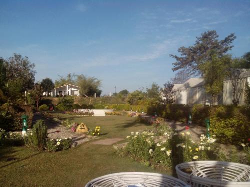 un jardín con flores y una casa de fondo en Hotel Clark, en Nueva Delhi
