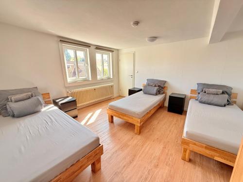 two beds in a room with wooden floors at Boardinghouse Zur Rose in Leidersbach