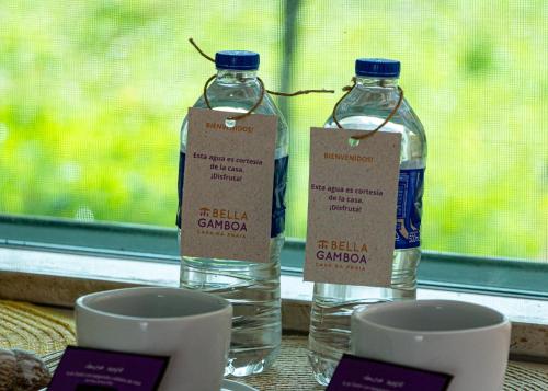 two bottles of water sitting on a table next to cups at Bella Gamboa Casa de Praia - Gamboa, Morro de São Paulo - in Gamboa