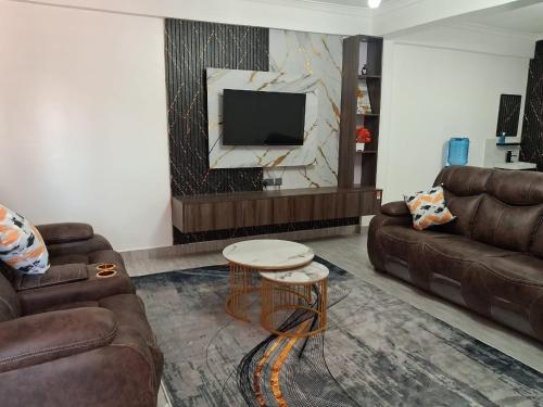a living room with two couches and a tv at Moonshine walkers furnished apartments in Munyu