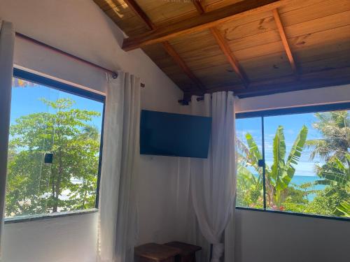 a room with a large window and a television at Casa Tiririca vista mar in Itacaré