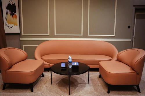 two orange chairs and a table in a room at Horizon Manor Hotel in Doha
