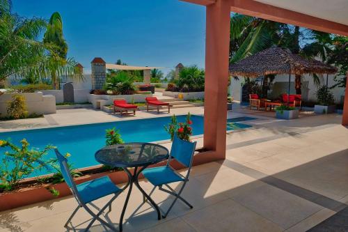 a patio with a table and chairs and a pool at Résidence Sarimanok in Nosy Be