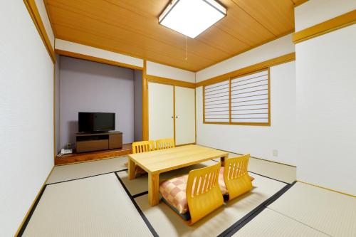 a room with a table and chairs and a tv at HOTEL MYSTAYS Hakodate Station in Hakodate