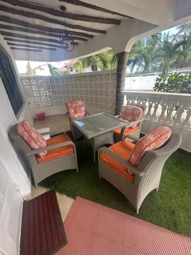 a balcony with chairs and a table and a table and chairs at Sea la vie - Macheo in Ukunda