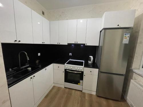 Una cocina con gabinetes blancos y un refrigerador de acero inoxidable. en Sunrise Guesthouse UB, en Ulán Bator
