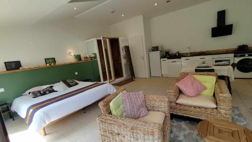 a bedroom with a bed and two wicker chairs at Domaine des Célestins - Loft Ginkgo in Bernay-en-Ponthieu