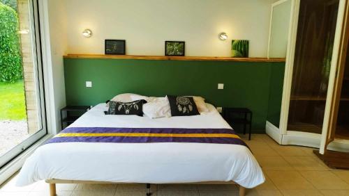 ein Schlafzimmer mit einem großen Bett mit einer grünen Wand in der Unterkunft Loft Ginkgo in Bernay-en-Ponthieu
