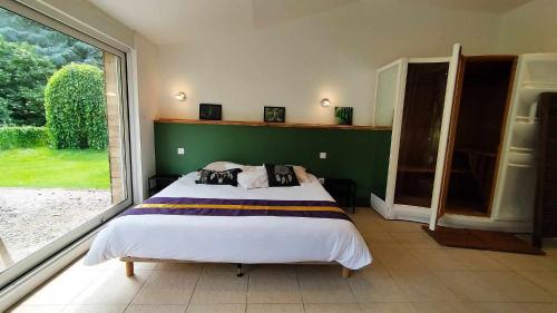 ein Schlafzimmer mit einem Bett und einem großen Fenster in der Unterkunft Loft Ginkgo in Bernay-en-Ponthieu