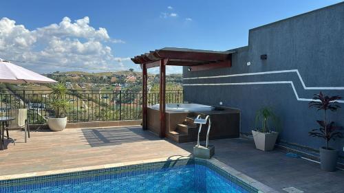 einen Pool mit Whirlpool auf einer Terrasse in der Unterkunft Chácara Gama em condomínio Igarata-SP - Jacuzzi com hidromassagem, piscina e sauna in Igaratá