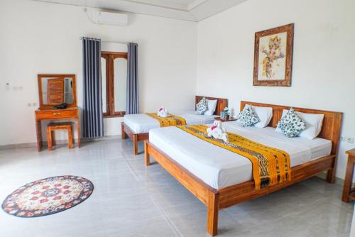 a room with three beds and a tv in it at Villa Jepun Lovina in Lovina