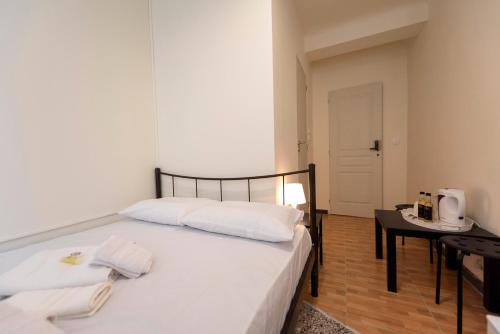 a bedroom with a bed with white sheets and a table at ATHENS COMMERCIAL in Athens