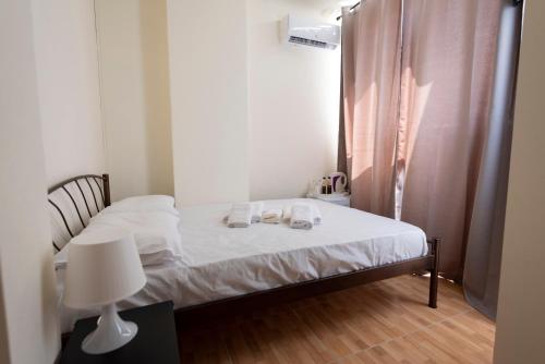 a small bedroom with a bed with white sheets and a lamp at ATHENS COMMERCIAL in Athens
