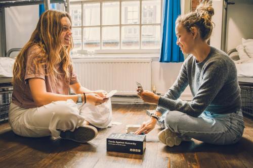 two women sitting on the floor looking at their cell phones at St Christopher's Inn London Bridge - The Inn in London
