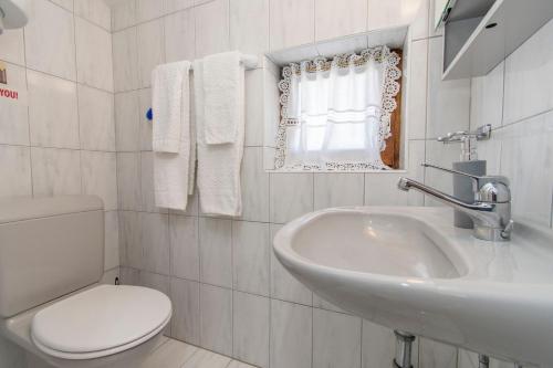 ein weißes Badezimmer mit Waschbecken und Toilette in der Unterkunft Apartments Emmeline in Tisno