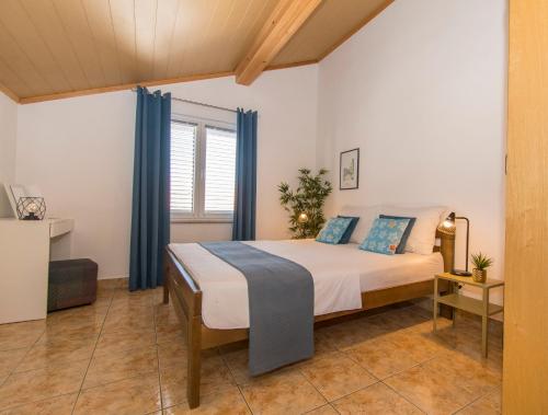 Schlafzimmer mit einem Bett mit blauen Vorhängen in der Unterkunft Apartments Emmeline in Tisno