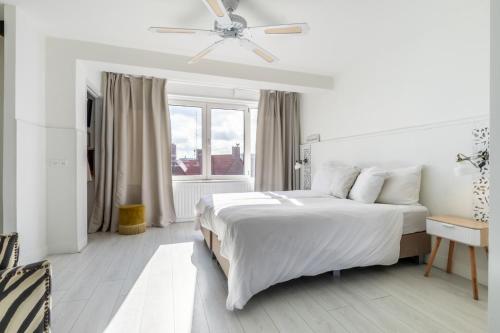 a white bedroom with a bed and a window at Rembrandts beach view in Zandvoort