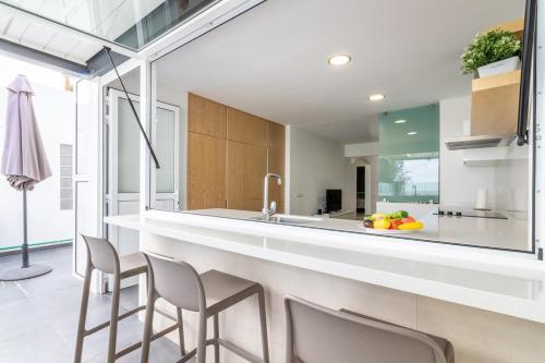 a kitchen with a long counter with stools at Bungalow Einstein Xej in San Bartolomé