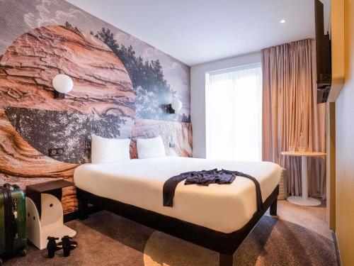 a hotel room with a bed and a mural at ibis styles Paris Montmartre Batignolles in Paris