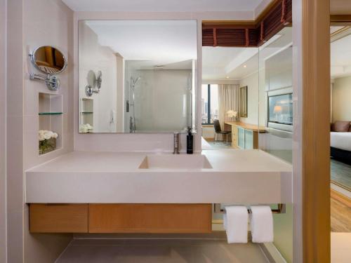 a bathroom with a sink and a mirror at Grand Mercure Bangkok Atrium in Bangkok