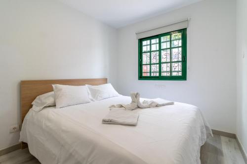 a white bed in a white room with a window at Bungalow Einstein Xej in San Bartolomé