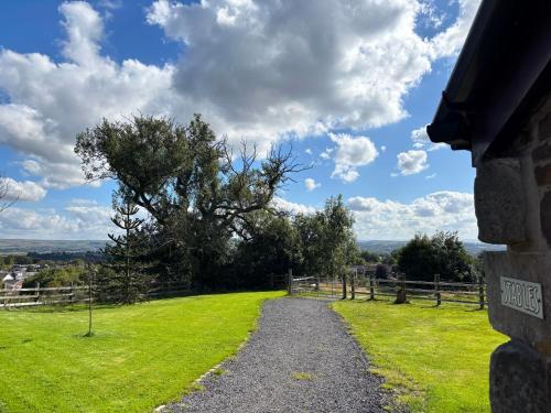 a gravel path leading to a field with a tree at Fernhill Hotel in Rochdale