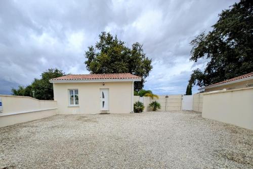 a white house with a fence and a driveway at L'échappée médocaine, deux maisons indépendantes in Cussac-Fort-Medoc