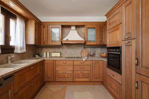 a kitchen with wooden cabinets and a sink at ZELION VILLA in Stelida