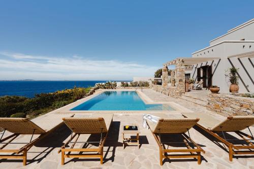 a villa with a swimming pool with chairs and the ocean at ZELION VILLA in Stelida