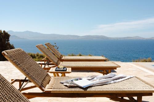 a group of chairs sitting on a patio near the ocean at ZELION VILLA in Stelida