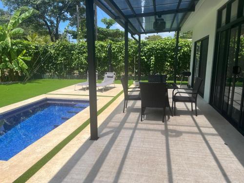 a patio with a table and chairs next to a pool at Casa Flor in Playa Avellana