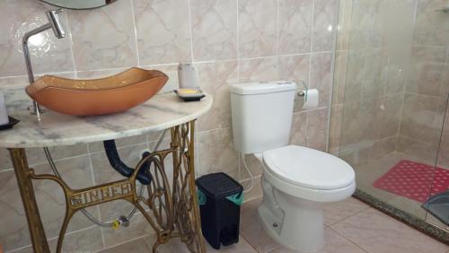a bathroom with a bowl sink and a toilet at Casa em poucos passos da praia de Jaconé in Maricá