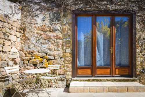 a wooden door of a stone building with a table and chairs at Maison en Pierre avec Jardin 4 Voyageurs in Luré